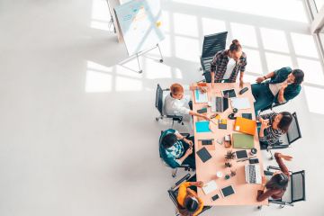 Informal meeting in spacious room with laptops and colourful office stationery.